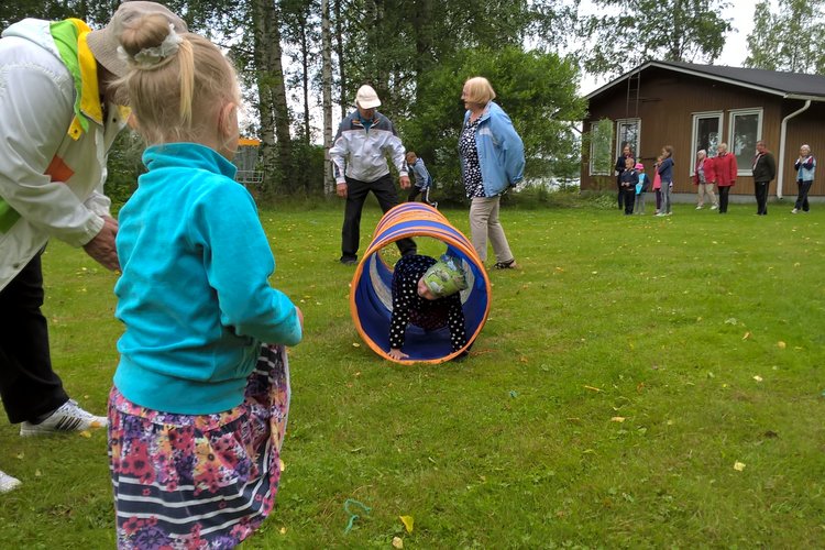 Lapset ja aikuiset leikkivät leirikeskuksen pihalla